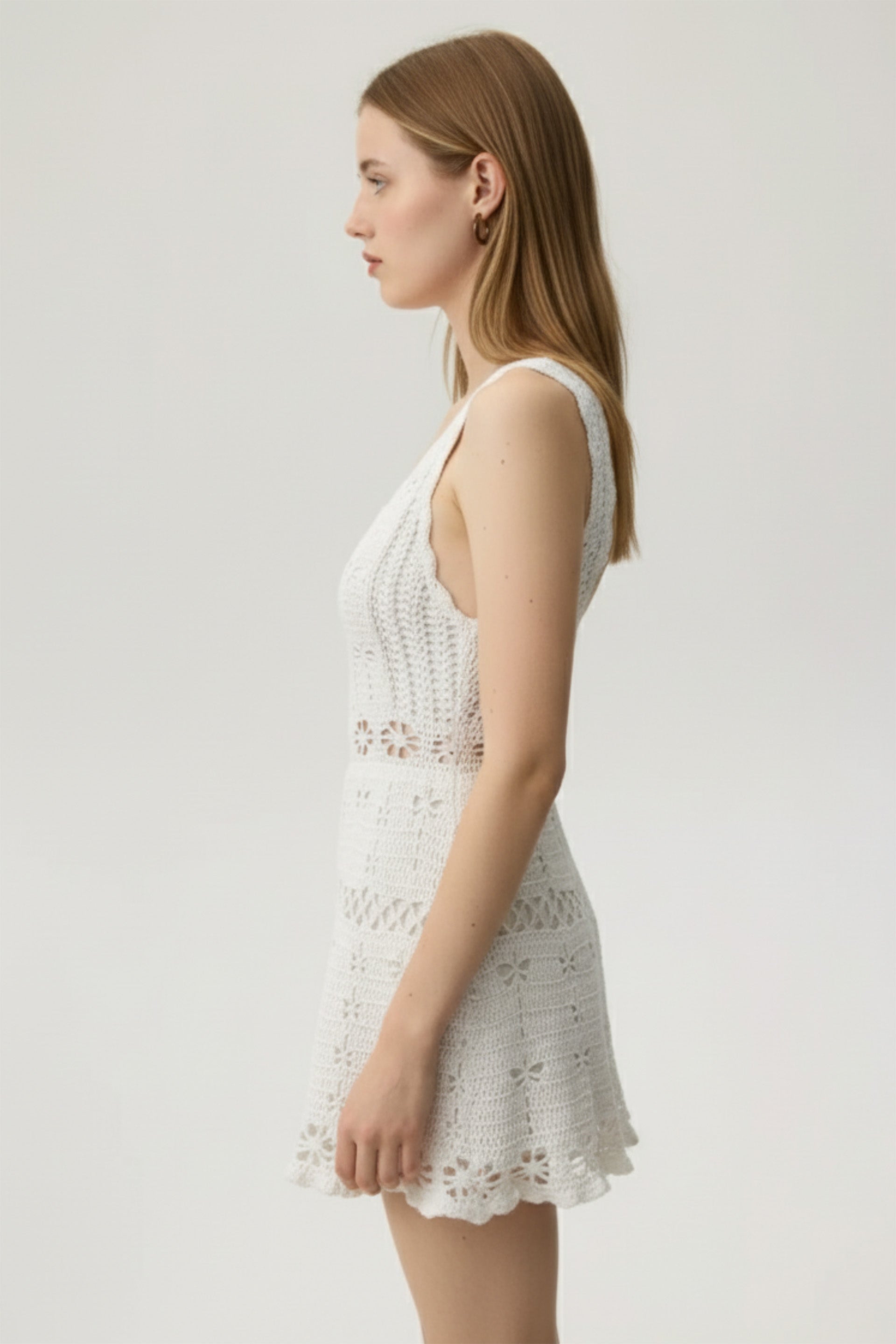 Woman wearing a white lace dress against a plain background