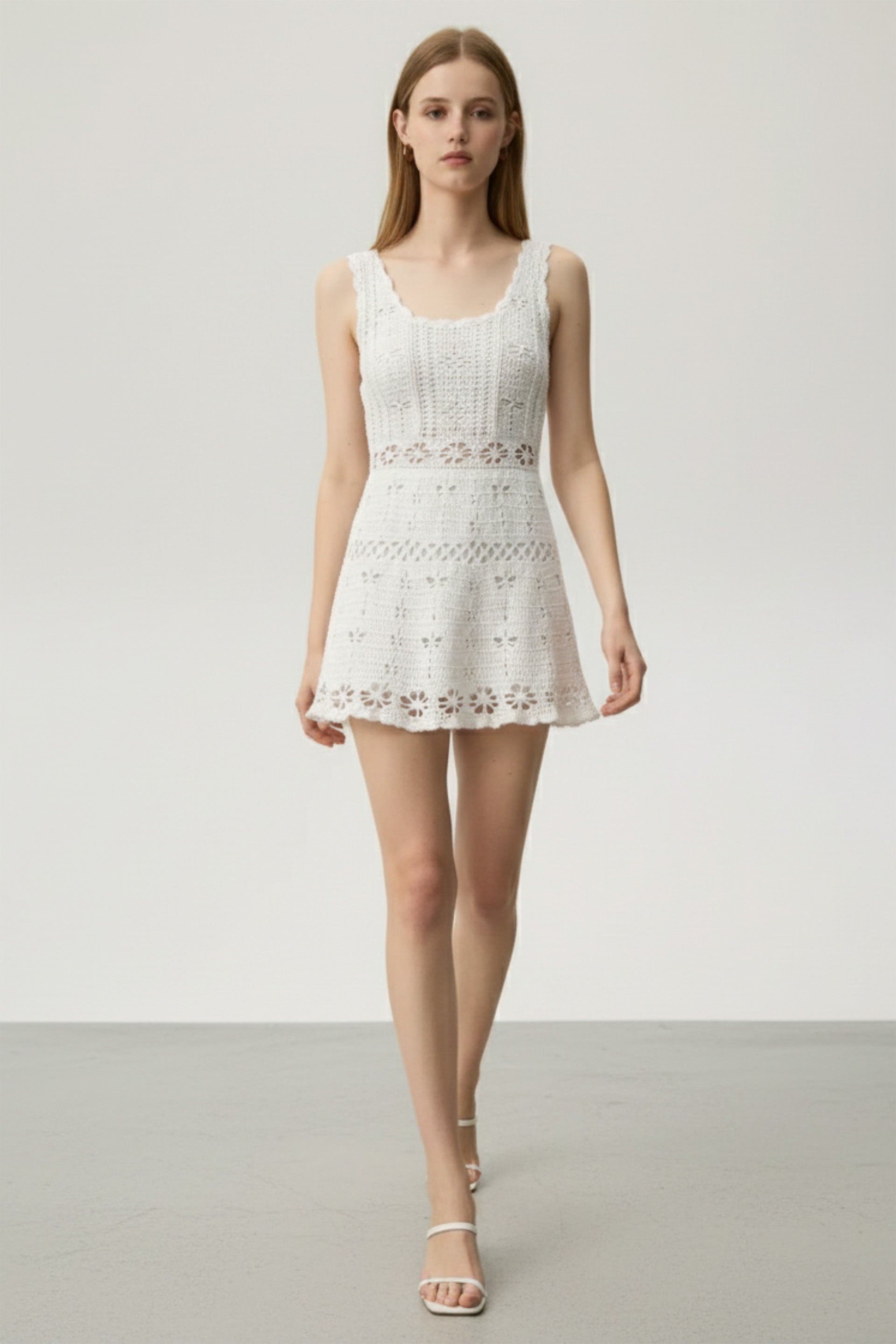 Woman wearing a white lace dress on a plain background
